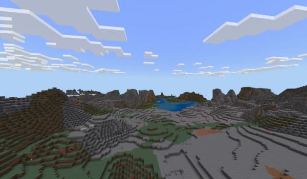 A person standing with a dog looking out over a mountainous landscape with a lake.