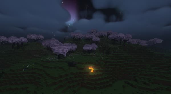 A person’s hand holds a small glass bottle of essential oil with a dropper.