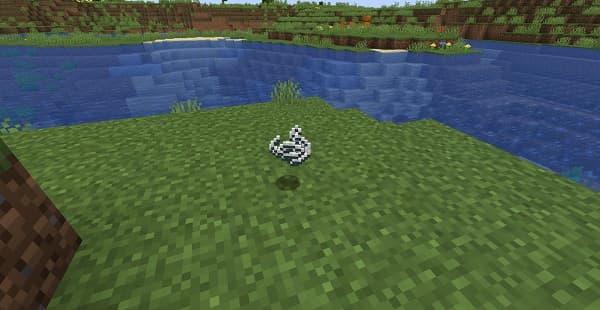 A sleek black cat stretches on a white sofa.