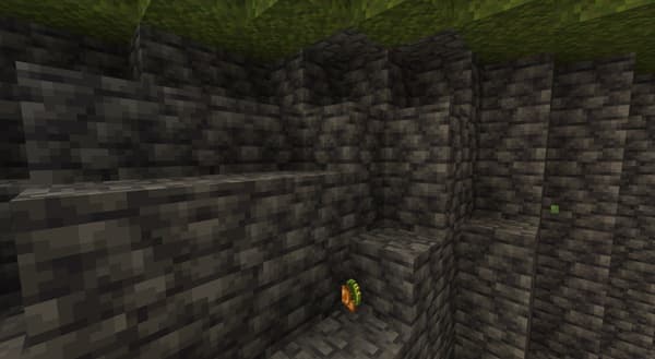 A stack of green, blue, and yellow folded towels with a leafy plant and white flowers on top.