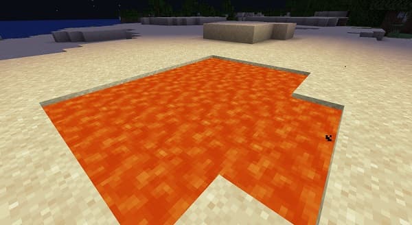 A small, fluffy white dog lying on a gray couch, looking up.