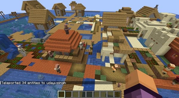 A person in a black shirt and jeans stands on a rocky beach with a mountain and ocean in the background.