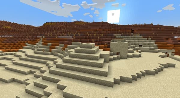 A red heart made of roses sits on a bed of green leaves.