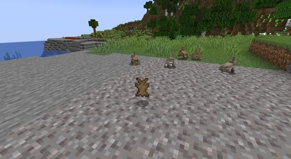 Brown teddy bear wearing a white t-shirt and blue jeans, sitting on a wooden bench.